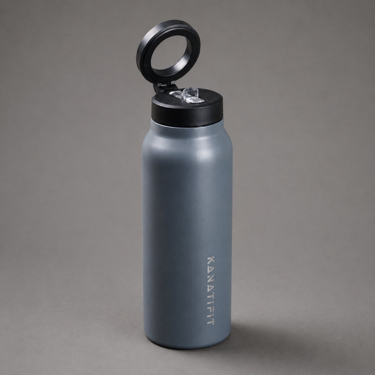 A matte slate water bottle with a black flip-top lid, shown with the lid open against a neutral gray background. The brand name 'KANATIFIT' is printed vertically on the front of the bottle.