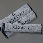 Three gray heathered sweat towels with black trim and the brand name KANATIFIT printed in black, arranged diagonally on a solid gray background.