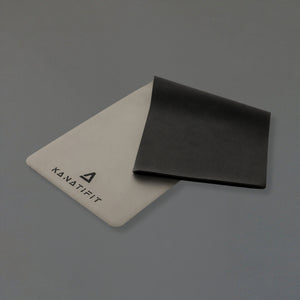 Two rectangular foam-like pads or mats on a plain gray background, one light beige with the 'KANATIFIT' logo and the other black, shown overlapping.