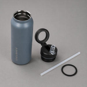 A matte slate insulated water bottle with a stainless steel interior, shown next to its open black lid, a clear straw, and a black ring on a neutral gray background. The brand name 'KANATIFIT' is printed vertically on the bottle.