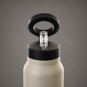 Close-up of a matte off-white insulated bottle with a black lid and a clear plastic straw spout, shown against a neutral gray background.